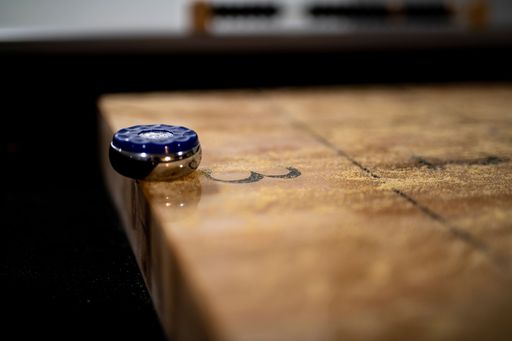 A selective focus shot of a puck on the edge of the table shuffleboard