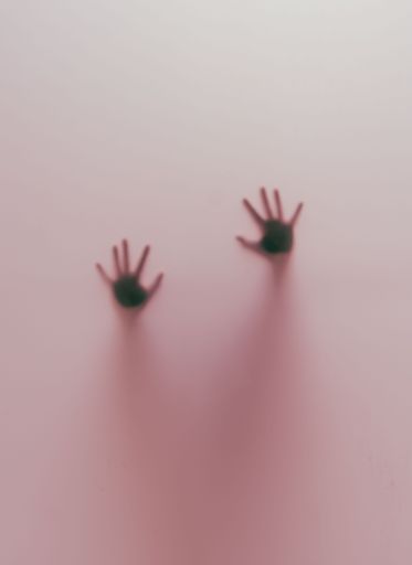 A vertical shot of blurred human hands behind a pink glass