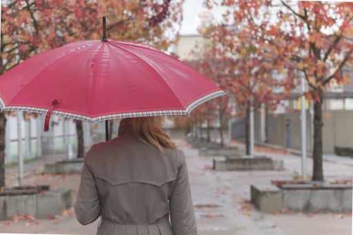 A closeup shot of a female with a red umbrella walking in th