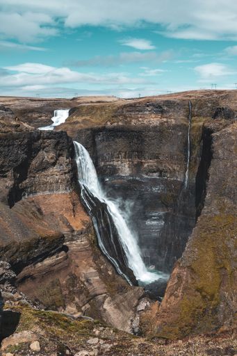 A vertical shot of a waterfall flowing down a rocky mountain