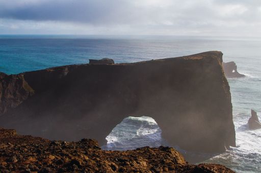 The Dyrholaey surrounded by the sea under the sunlight and a cloudy sky in Iceland