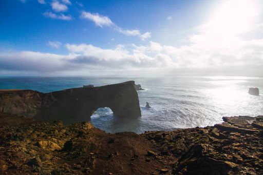 The beach surrounded by the sea under a cloudy sky and sunlight in Iceland