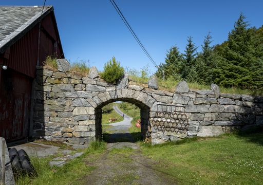 An old stone bridge surrounded by different kinds of trees and greenery in Norway