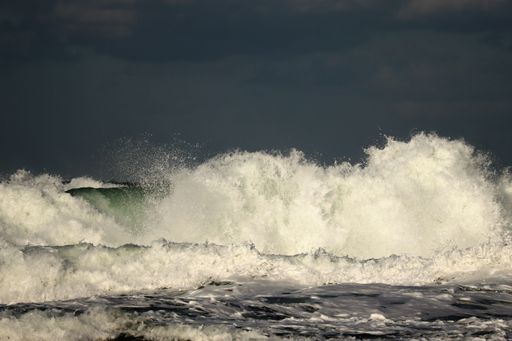 Dark green waves with foam and splashes move towards the shore during a morning storm