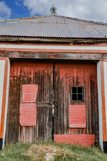A vertical shot of an old rural wooden red and brown door of a hut