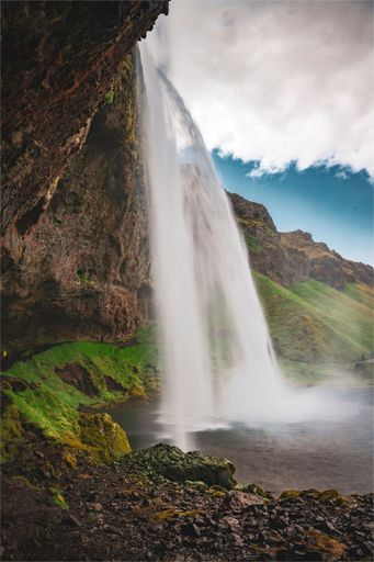A majestic Seljalandsfoss waterfall cascades down behind a rocky outcrop in Iceland.