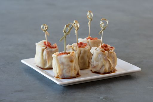 A closeup of delicious dim sum Chinese dumplings served on a plate with wooden sticks