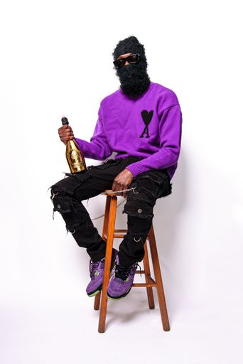A vertical shot of the man wearing a face cover with glasses and holding a bottle of champagne