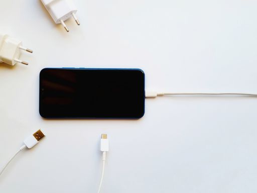 A top view of a smartphone and USB charging cable on a white background