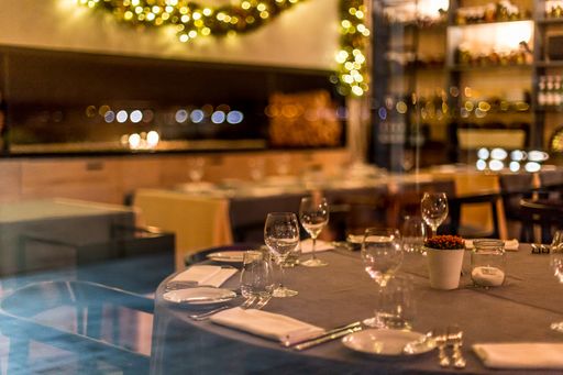 A high angle shot of plates and glasses on the table in a restaurant with a blurred background