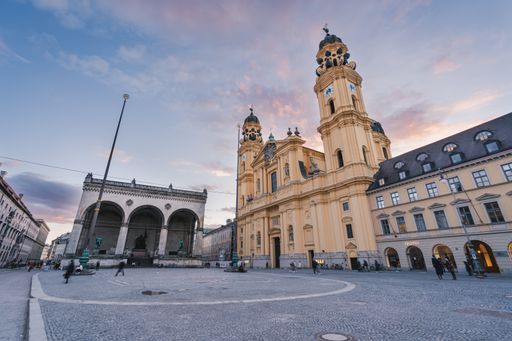 The Odeonsplatz during a breathtaking sunset in Munich. Many people and tourist walking across the square in the evening.