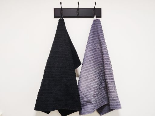 Two towels hanging on a holder on a white wall