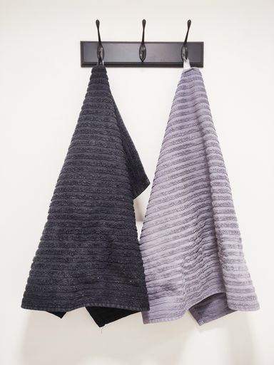 Two towels hanging on a holder on a white wall