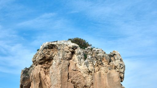 A scenic view of a rocky cliff in Torre del Mar, Spain against a wispy sky background