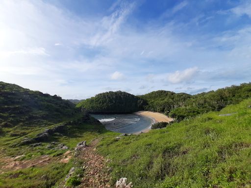High angle view from a hill top on the lagoon sand beach called Pantai Kasap, surrounded from mountains and rain forest on Java, Indonesia