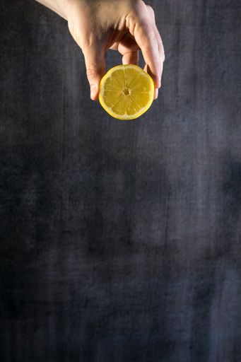 A hand holding half of a lemon in the grunge texture background with a copy space