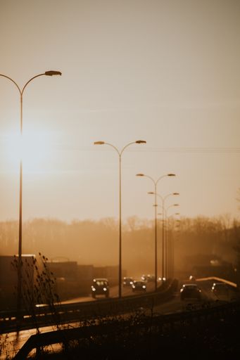 A vertical shot of street lights along the road at sunset