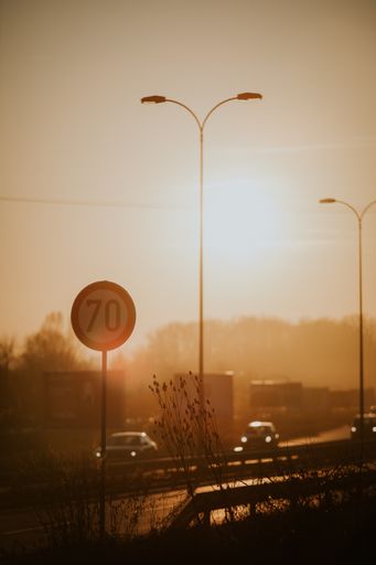A vertical shot of a round speed limit road sign on the road at suns