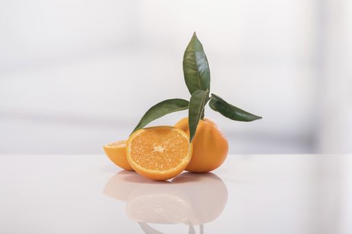Fresh oranges with green leaves and next to it a cut orange on a light background. selective focus. vitamin and healthy food