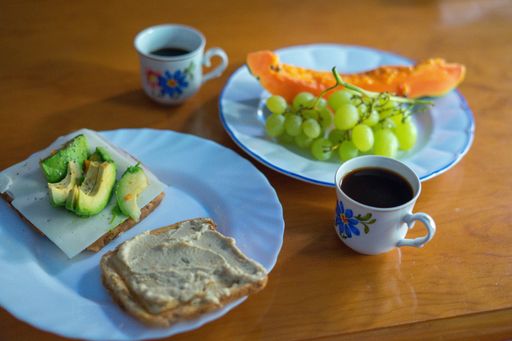 A selective focus shot of plates with avocado toasts and fruit with coffee for breakfast