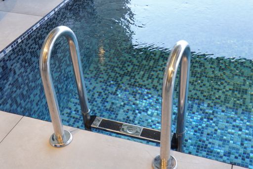 A high angle shot of a stainless steel ladder on a swimming poo