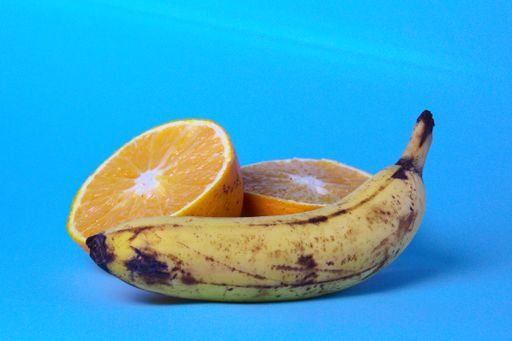 A closeup shot of sliced orange with banana on blue background