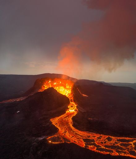 A stunning view of the eruption of Fagradalsfjall volcano in Iceland, with a vibrant orange hue emitting from the lava