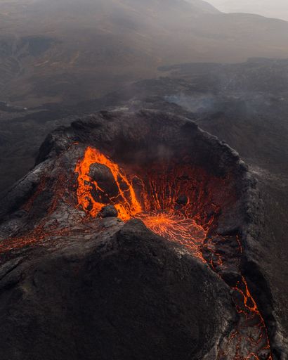 A view of Fagradalsfjall volcano crater in Iceland, with a vibrant orange hue emitting from the lava
