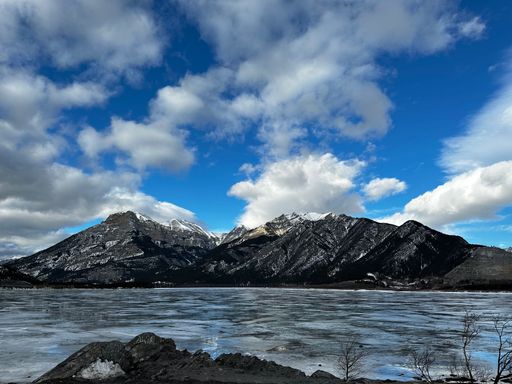 The beautiful half-frozen lake and mountains against the background of the cloudy blue sky. Canada.