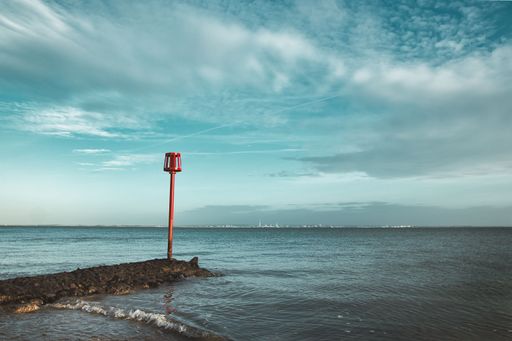 A picturesque waterfront scene featuring a red post warning boat situated in the foreground