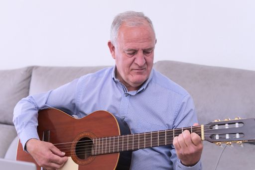 A Caucasian male playing guitar at home