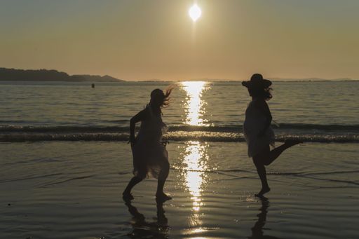 The silhouettes of young women having fun on a beach during sunset