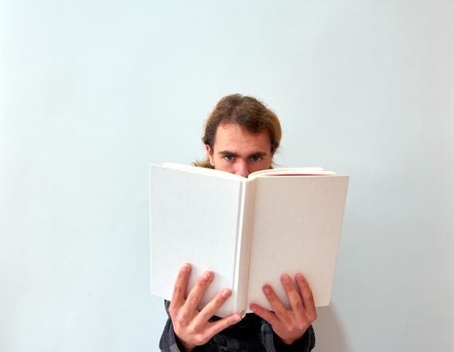 A Caucasian man reading a book on the background of white wall