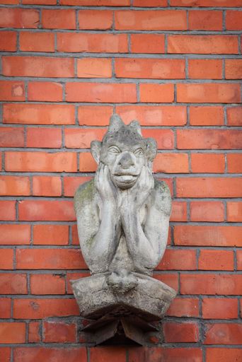 A vertical shot of a historic gargoyle statue on a brick wall in Smithfield, Dublin, Ireland