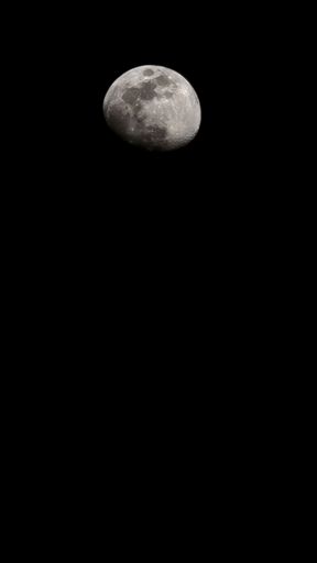 A partially lit moon against dark sky