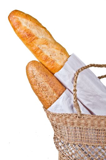A vertical shot of baguette bread on woven basket isolated on white background