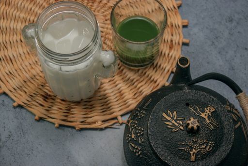 A closeup shot of matcha tea mixed with sugar and honey and a glass full of ice and milk - matcha tea preparation