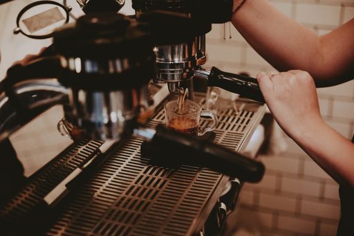 A female barista using the coffee machine and making a delicious latte