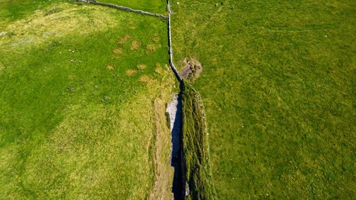 Connacht 2022. Vertical view of a crevasse in a green hill near the sea. We are on a sunny summer day. August 2022 Connacht, Ireland