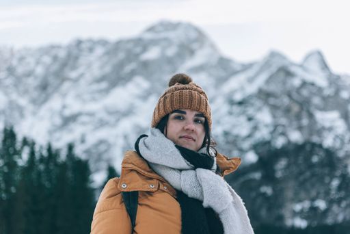 A portrait of a female standing in front of snow-capped Mount Mangart in Julian alps