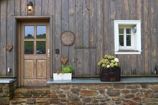The front of the wooden house with doors, white window and flowers at Czech republic