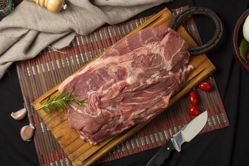 A high angle show of raw meat on a board with ingredients on the table