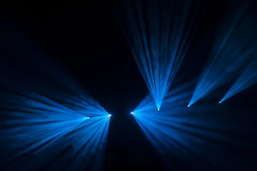 A blue laser party lights against black background on the studio