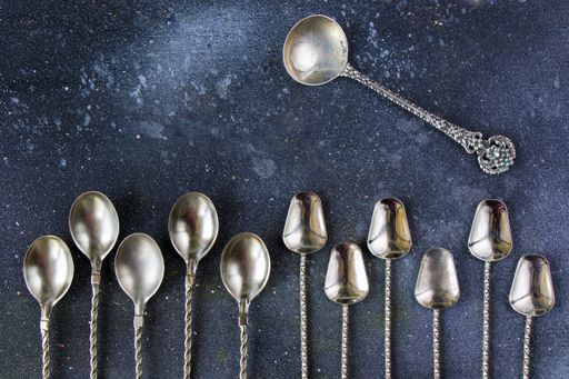 A top view of a collection of different vintage spoons on the table under the lights