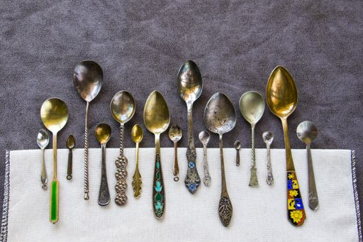 A top view of a collection of different vintage spoons on the table under the lights