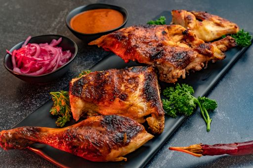 A closeup shot of deliciously prepared chicken served with onions and chili sauce