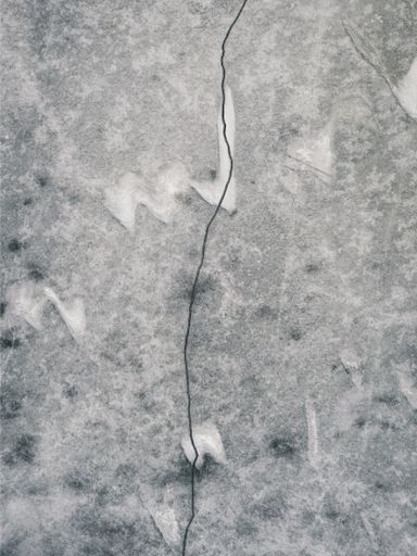 Aerial drone imagery of a crack through the ice on a frozen Midwestern lake during winter.