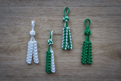 A selection of whtie and green decorative handmade rope ornaments arranged on a wooden table surface