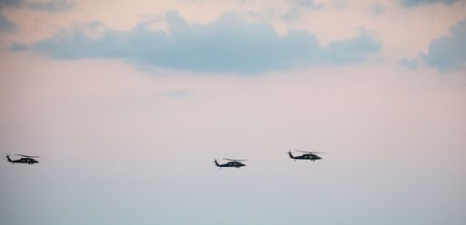 A wide angle of the military helicopters in the air during the air show at sunset