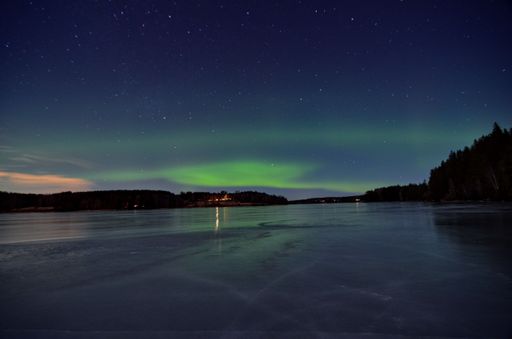 A breathtaking view of a lake illuminated by the dramatic Aurora Borealis in the night sky